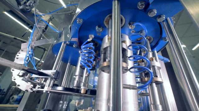 Factory machine places caps, close up.