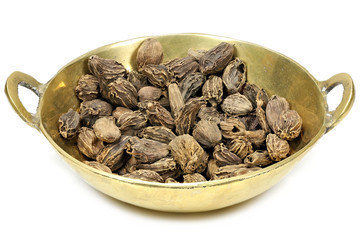 black cardamom in a brass bowl isolated on white background