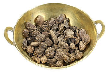 black cardamom in a brass bowl isolated on white background