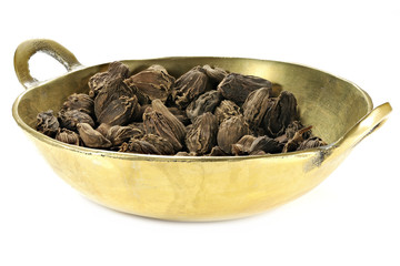 black cardamom in a brass bowl isolated on white background