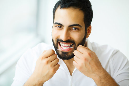 Dental Health. Man With Beautiful Smile Flossing Healthy Teeth. High Resolution Image