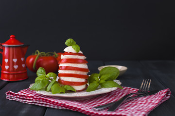 Traditional Italian Caprese Salad - sliced tomatoes, mozzarella cheese and basil, dark background, top view, copyspace. Caprese Salad, italian mediterranean food. text
