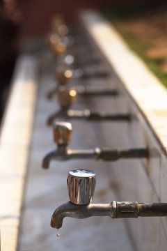 A sequence of faucet with copper handles in which water has reached a limit in hot sunny day, and only in one there was one drop of water.