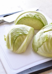 a head of fresh cabbage on a white cutting board ready to be cut and prepared