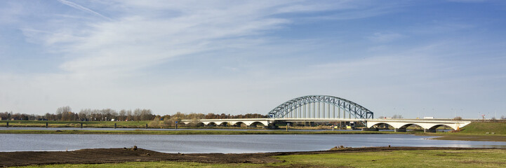 Typical Dutch river IJssel landscape with blue sky, white clouds, wind and sunny weather