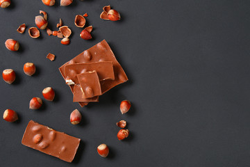 Chocolate with hazelnuts, mint and grains of coffee on a dark gray table. Top view. Copy space.