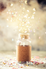 Creative concept photo of glass jar with confetti bursting out on light background. Copy space
