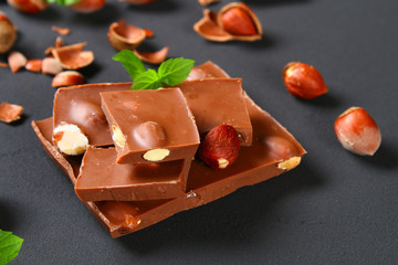 Chocolate with hazelnuts, mint and grains of coffee on a dark gray table.