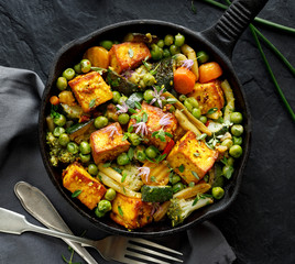 Tofu mit Gemüse bestreut mit Kräutern und essbaren Blumen, Ansicht von oben. Veganes Gericht lecker und nahrhaft. Konzept für gesunde Ernährung