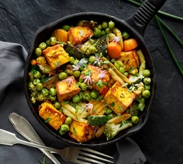 Keuken foto achterwand Gerechten Tofu met groenten bestrooid met kruiden en eetbare bloemen, bovenaanzicht. Veganistisch gerecht heerlijk en voedzaam. Gezond eetconcept