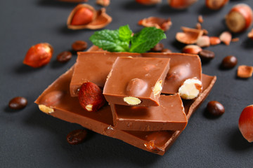 Chocolate with hazelnuts, mint and grains of coffee on a dark gray table.