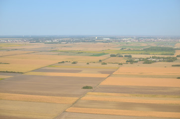 Fototapeta na wymiar Plains with different crops and plants and a city suburb seen from a landing plane