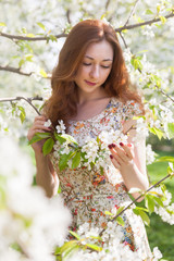 Fototapeta premium Young ginger hair woman near white tender blossoming tree. fairy dreamlike mood of the spring and summer. Beautiful romantic lady smiling bride, wedding. Copy space background.