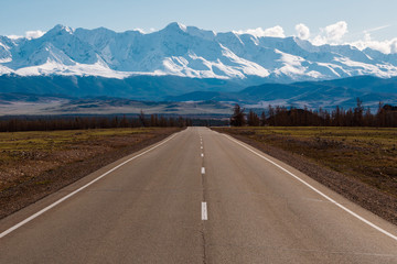 empty highway leading to the mountains with snow caps. Altai mountains landscape