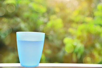 Blue plastic cup with water inside and blurred bokeh background