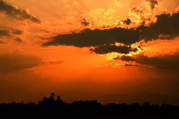 Orange light and dark clouds on sky over the mountain before sunset in the evening.