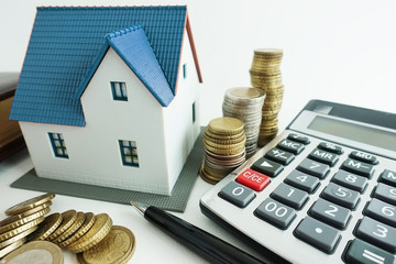 House purchase calculation with small model house, calculator and cash money, investment analysis...