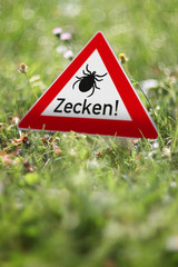 Schild mit Warnung vor gefährlichen Zecken im eigenen Garten