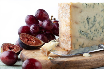 Stilton on a cheese board with red grapes, fig and cheese knife