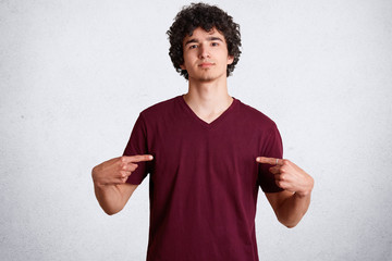 Portrait of handsome young male indicates at blank space of casual t shirt for your advertisement...
