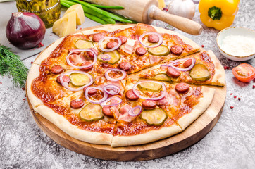 Homemade Meat Loves Pizza with pepperoni sausage, bacon, onions, cucumber, tomatoes, cheese on a wooden board, background, restaurant menu concept. Italian food style, close up.