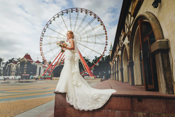 Bride in the park on the background of ferris wheel.