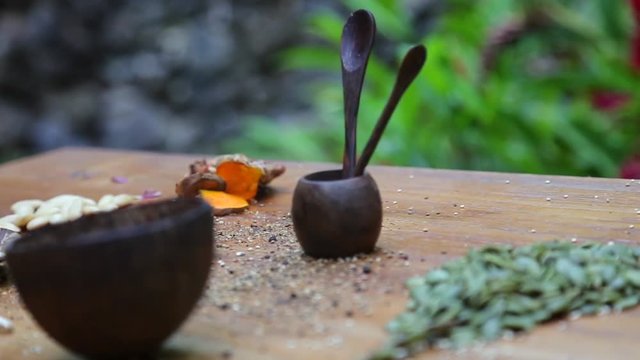 2 wooden spoons, chopsticks with rice, curcuma, pumpkin seeds on the background
