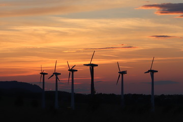 Wind power station in sunset. Romantic evening and modern technologies of ecologically clean electricity. Protection of the environment. Bright Future. An alternative way of extracting energy.