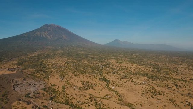 Aerial view volcano and mountains against the blue sky, volcanic, mountain landscape, Bali, Indonesia. Conical volcano of Gunung Agung. 4K, Aerial footage.
