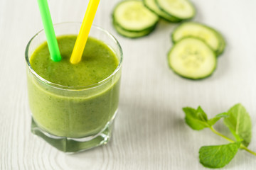 A glass of green vegetable smoothies on a white wooden background