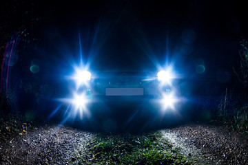The car stands on the territory of the house at night. Light headlights through the fence