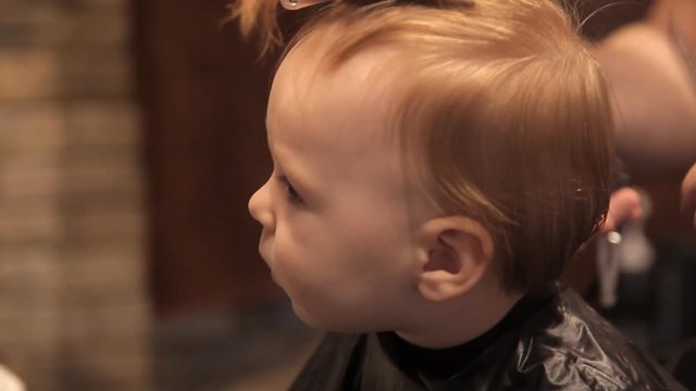 In a brutal hairdresser's, a young child is being sheared by a clipper