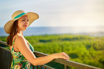 Fototapeta premium Woman wear hat looking to the sea and seagull crowd on sunset time. Young asian girl wearing hat looking away to the sea.