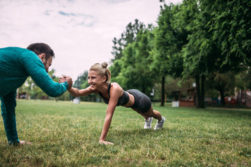 Two fit young people clapping hands from plank position during partner workout.