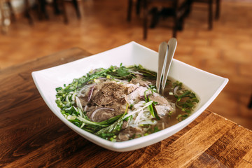 Delicious meal. Soup with vegetables and meat in a white ceramic plate. Pho bo.