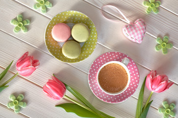 Macarons, espresso in pink cup, freesias and pink tulips, top view