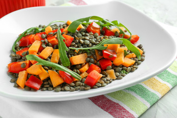 Plate with tasty lentil dish on table