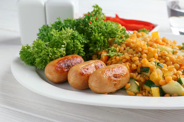 Plate with delicious lentil, sausages and vegetables on wooden table, closeup