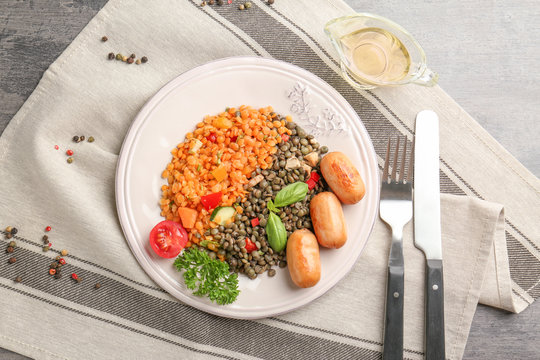 Plate with delicious lentil, sausages and vegetables on kitchen table