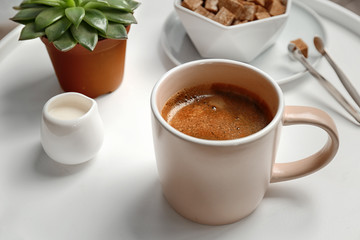 Cup of delicious hot coffee on table