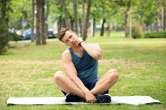 Male athlete suffering from neck pain during training outdoors