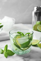 Refreshing beverage with mint and lime in glass on table