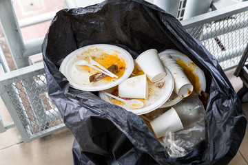 Environment unfriendly styrofoam plates and cups in plastic garbage bag