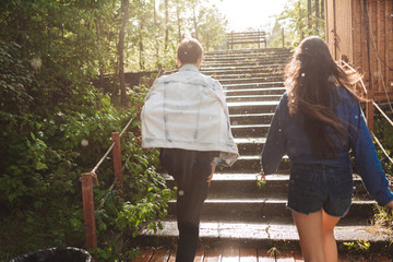 Beautiful photo of young couple from back going away under rain in park