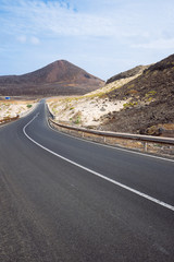 Desolates straight road over a surreal landscape with majestic volcano creater in the distance. Sao Vicente Cape Verde