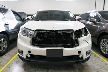 Wrecked and damaged white vehicle in shop