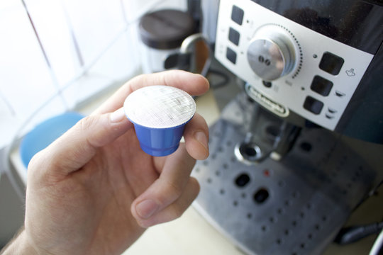 Coffee Capsule/pods In A Hand. Coffee Machine In Background 