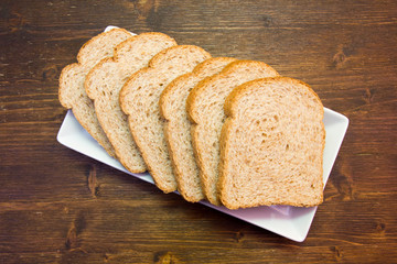 Slices of wholemeal bread on a wooden table viewed from above