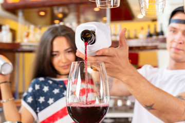 Bartenders pouring red wine from a bottle in a wine glass, Close-up
