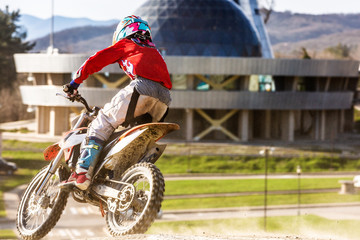 Moto cross biker at race- a sharp turn and the spray of dirt, rear view - close up